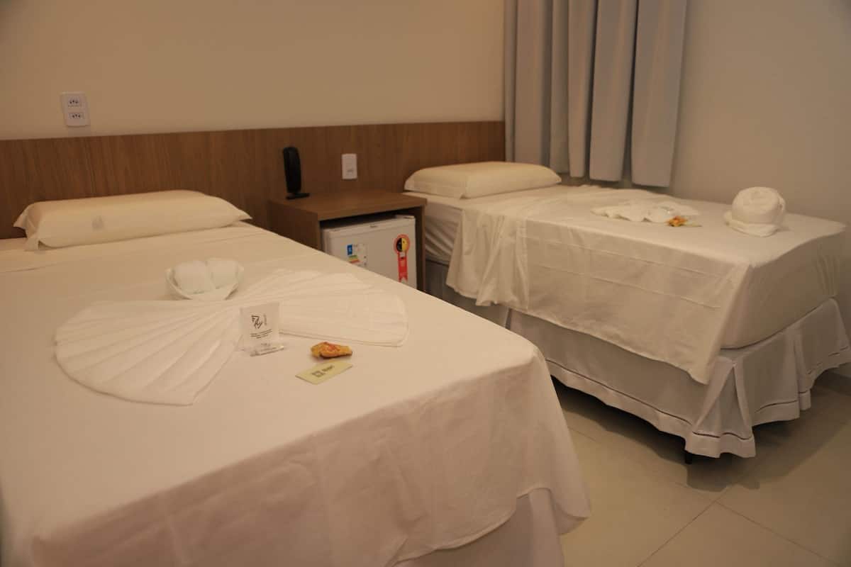 Una habitación de hotel con dos camas, una mesita pequeña y una mesilla de noche.