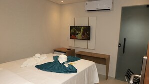 Ein Hotelzimmer mit Bett, Schreibtisch, Fernseher und Klimaanlage.