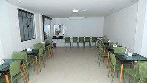 Ein Konferenzraum mit grünen Stühlen und Tischen, einem großen Fenster und einer weißen Wand.