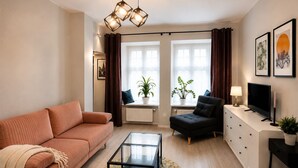 Un salon moderne avec un canapé, un fauteuil, une table basse, un téléviseur et des œuvres d’art accrochées au mur.