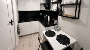 Une cuisine moderne avec des meubles blancs, des plans de travail noirs et une palette de couleurs en noir et blanc.