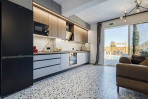 A modern kitchen with a built-in microwave, a dishwasher, and a large refrigerator. - Nightingale Alexander Villa - private pool (Paleokastritsa)
