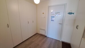 Een gang met een witte deur, een ventilatie rooster en een welkomstbord.
