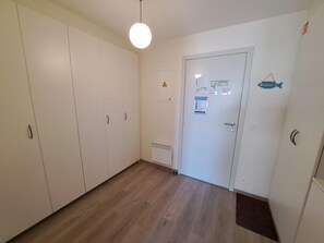 Ein Flur mit einer weißen Tür, einem Lüftungsgitter und einem Willkommensschild.