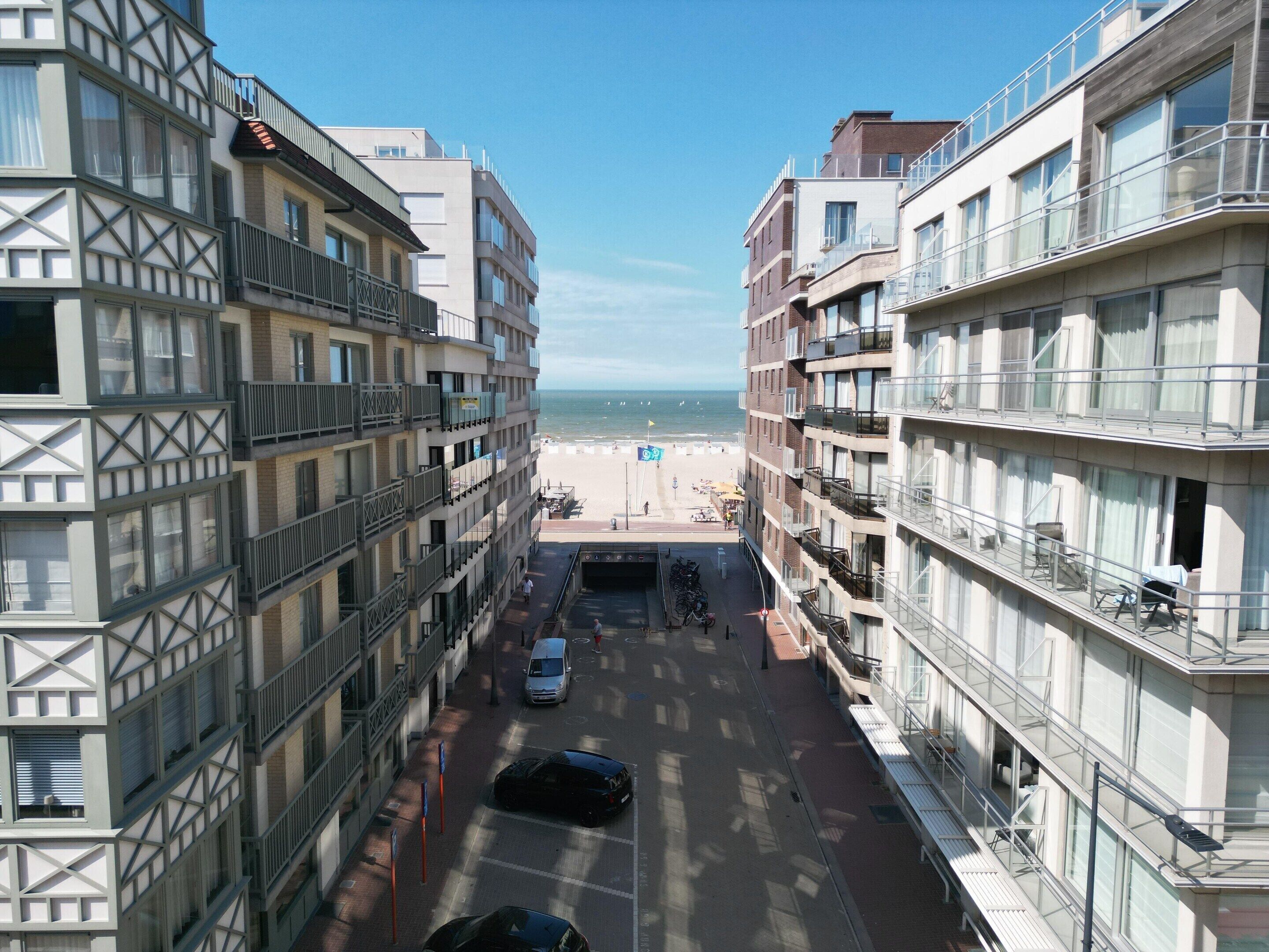 Ein mehrgeschossiges Gebäude mit Balkonen, einem Parkplatz und Blick auf den Strand.