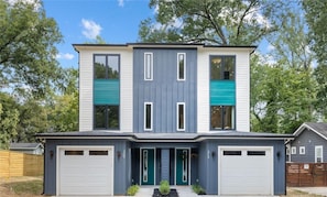 Ein modernes, zweistöckiges Haus mit Garage, großen Fenstern und einer Veranda.