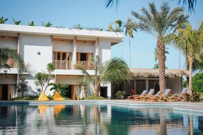 Una piscina al aire libre, sombrillas, sillones reclinables de piscina