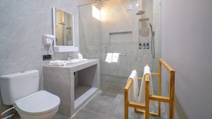 A modern bathroom with a toilet, sink, mirror, shower, and wooden chair. - Giri Rose Boutique Hotel (Kuta)