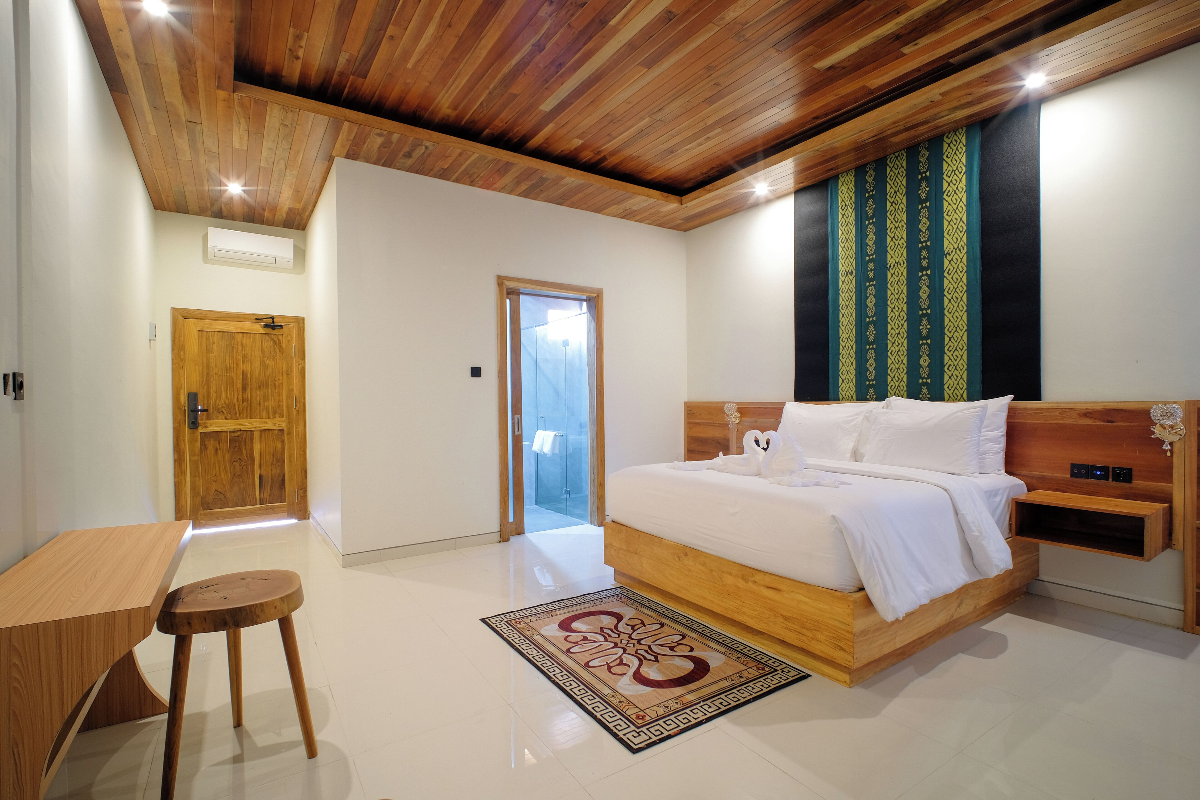 A bedroom with a wooden ceiling, a bed with white bedding, a wooden nightstand, and a small stool.