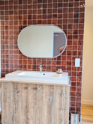 A bathroom with a wooden vanity, a white sink, and a mirror. - Maison Millefeuille Bed and Breakfast: Between the Forest and the Marshes, Just 10 Minutes from the Beaches! (Saint-Hilaire-de-Riez)