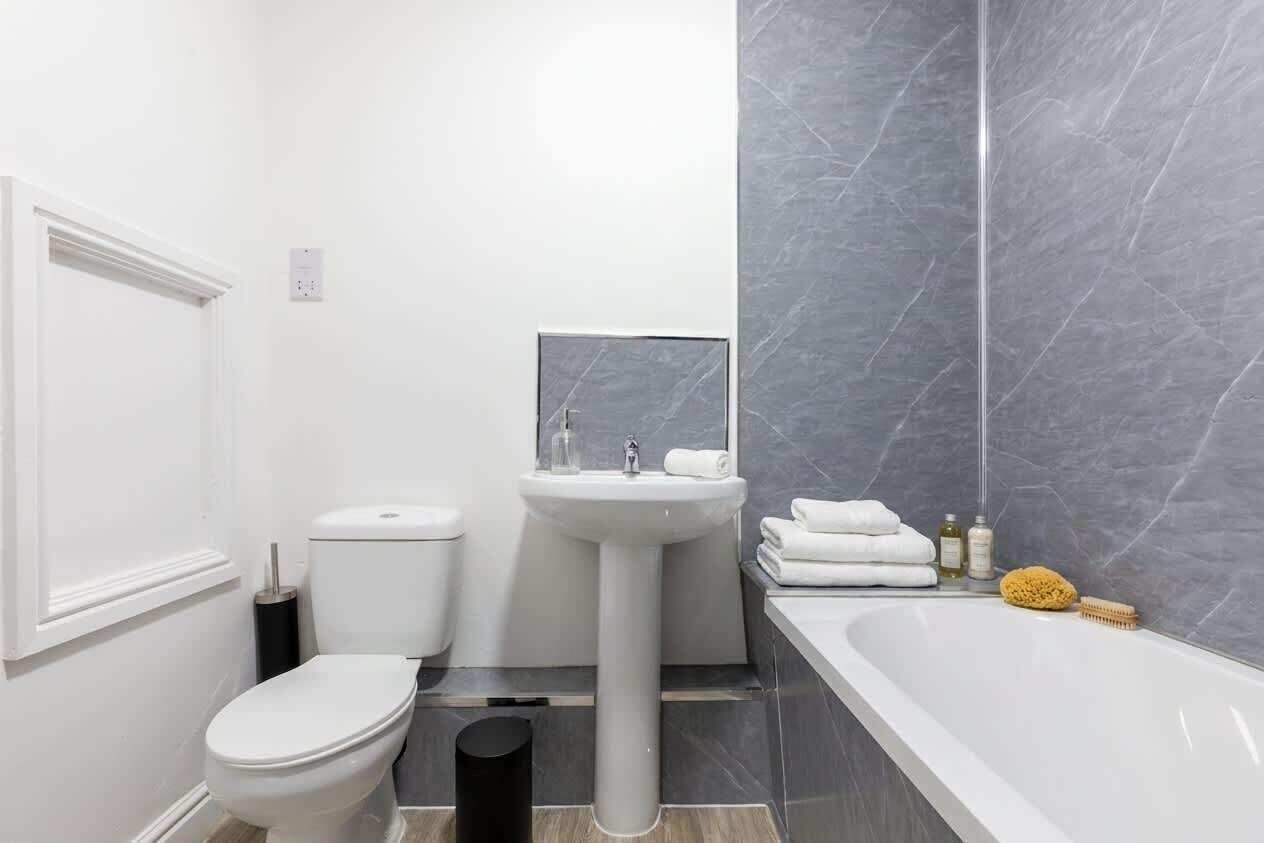 Een moderne badkamer met toilet, wastafel en bad.