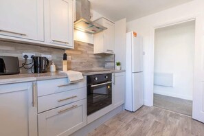 Una cocina moderna con armarios blancos, horno empotrado y campana extractora de acero inoxidable.
