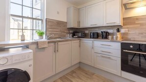 A modern kitchen with white cabinetry, a built-in microwave, and a dishwasher. - Modern 2BR Sea View Flat on the Harbour (Whitehaven)