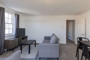 Un salon moderne avec un canapé, un téléviseur et une table à manger.