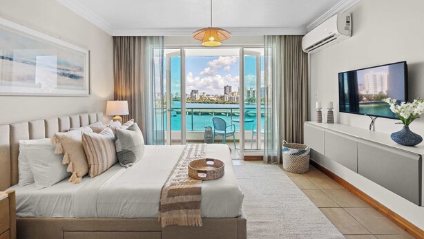 Een moderne hotelkamer met een groot bed, een televisie, een balkon met uitzicht op de stad en een airconditioning.