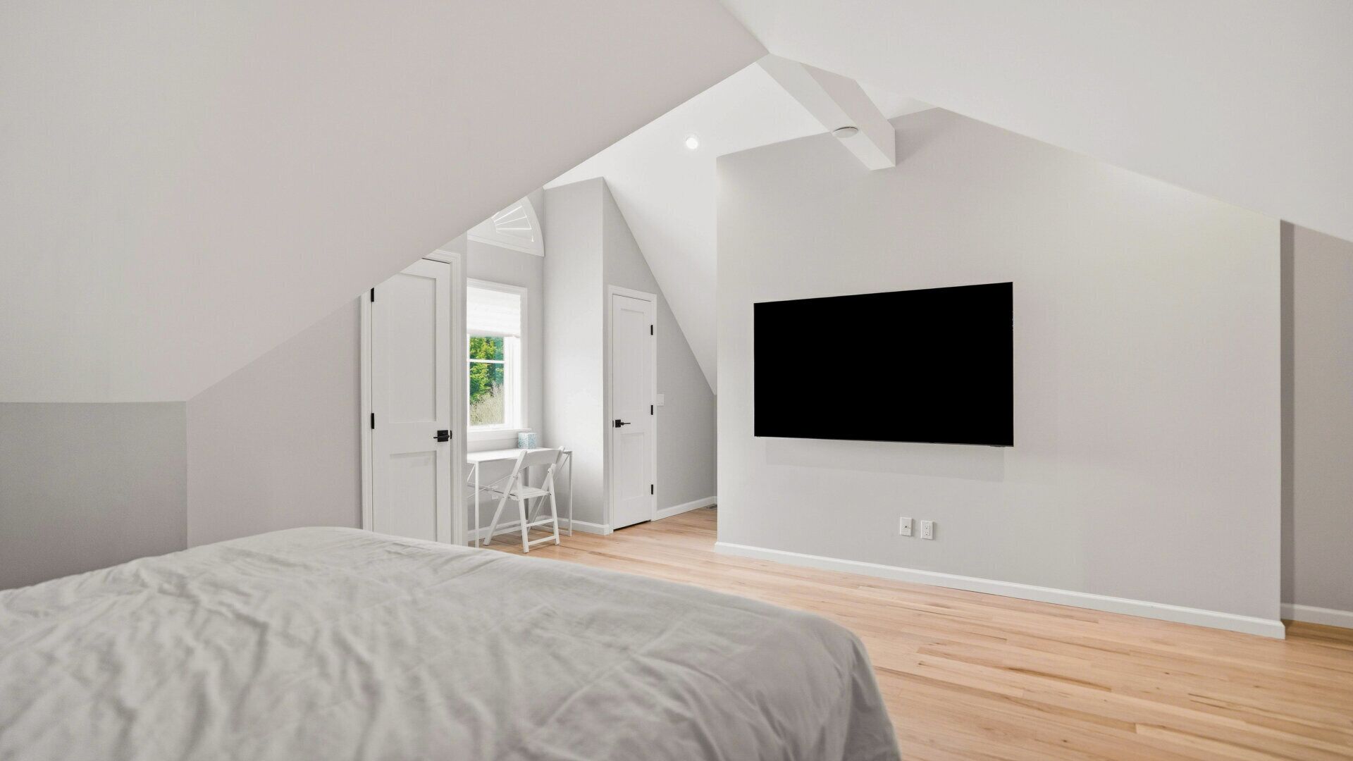 Una camera da letto moderna con un letto grande, una scrivania e una TV a parete.