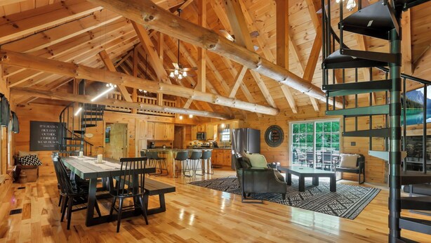 Un interior espacioso de madera con comedor, cocina y una escalera de caracol.