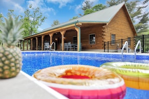 A wooden cabin with a pool, outdoor seating, and a covered patio. - The Johnny: Sleeps 16 w/ Brand-New Pool, Hot Tub, Firepit & Private Pond (Laurelville)