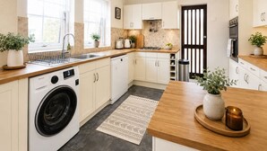 A modern kitchen with a washing machine, a stove, and a sink. - Manor Road Retreat | Modern | Sleeps 5 (London Colney)
