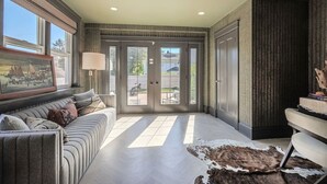 A spacious living room with a sofa, a rug, and a door leading outside. - Loose Park Modern Mansion (Kansas City)