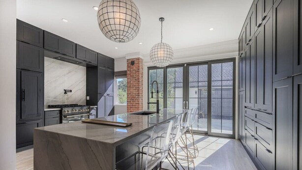 A modern kitchen with a marble island, stainless steel appliances, and a large window. - Loose Park Modern Mansion (Kansas City)