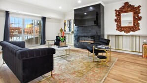Een moderne woonkamer met een open haard, een zwarte leren bank en een ronde salontafel.