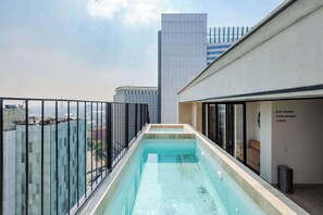 A rooftop swimming pool with a glass barrier, a high-rise building in the background, and a sign indicating 'ROOF GARDEN.' - Colon: Loft with private balcony and Rooftop Pool (Ciudad de México)