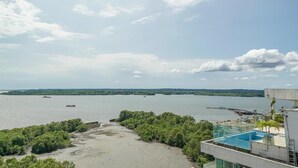 A view of a river with boats, a building with a pool, and surrounding greenery. - Hotel Yubarta (Buenaventura)