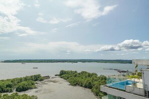 A view of a river with boats, a building with a pool, and surrounding greenery.