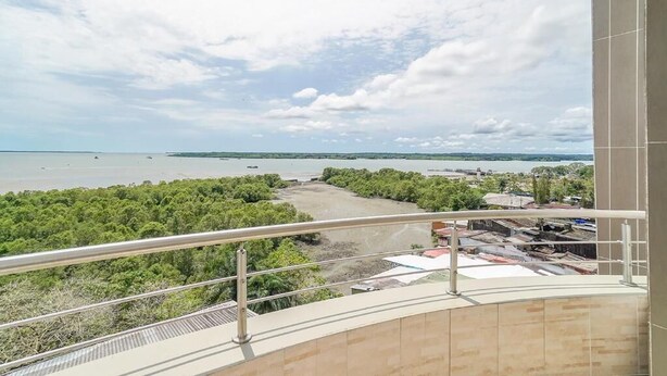 A balcony with a view of a body of water, greenery, and distant buildings. - Hotel Yubarta (Buenaventura)