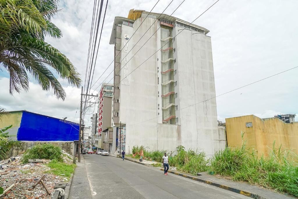 A tall concrete building with multiple floors, a street in front, and a blue tarp on the left.