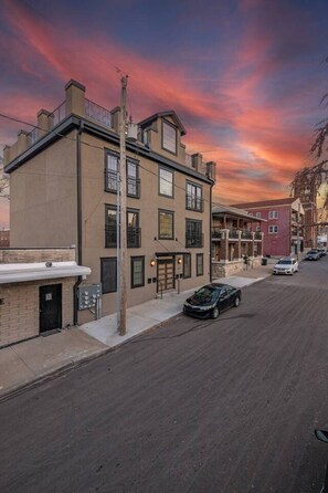 A multi-story building with a flat facade, a visible entrance, and a parked car on the street. - Huge Modern Penthouse Skyline View and RooftopDeck (Kansas City)