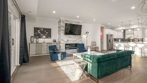 Ett modernt vardagsrum med en grön soffa, en blå fåtölj och en öppen spis.
