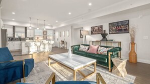 Una sala de estar moderna con un sofá verde, una mesa de centro de mármol y sillones azules.