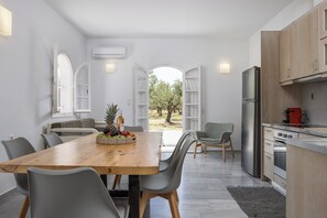 Eine moderne Küche mit einem Holztisch, grauen Stühlen und einer Obstschale.