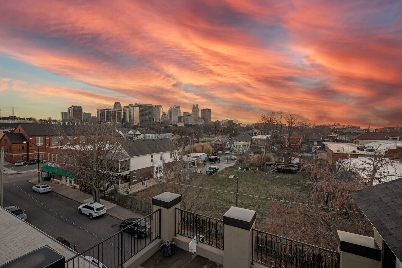 A cityscape with a sunset sky, buildings, and a parking lot.