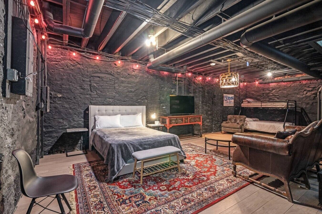 A room with a bed, a sofa, a small table, and a TV.