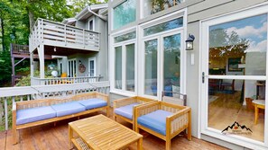 A wooden deck with outdoor seating, a covered area with a railing, and a large sliding glass door. - Skyleaf A5 • Bright Mountain Escape (Sugar Mountain)