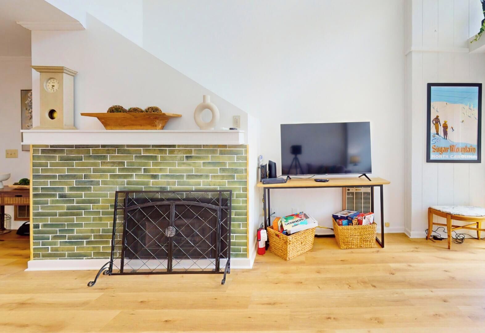 Ein Wohnzimmer mit Kamin aus Backsteinen, einem Fernseher und einem gerahmten Bild an der Wand.