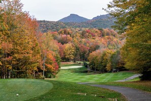 A golf course with a pond, surrounded by autumn-colored trees and a mountain in the background. - Skyleaf A5 • Bright Mountain Escape (Sugar Mountain)