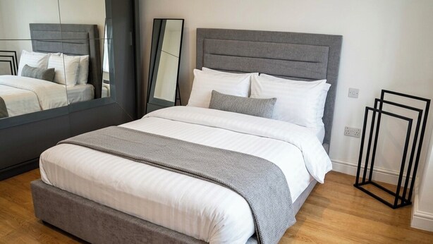 Un dormitorio moderno con una cama grande, un espejo y una mesita de noche.