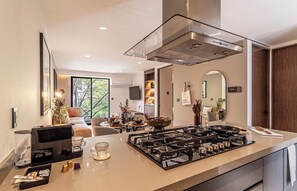 Una cocina moderna con estufa a gas, cafetera y vistas al área de estar.