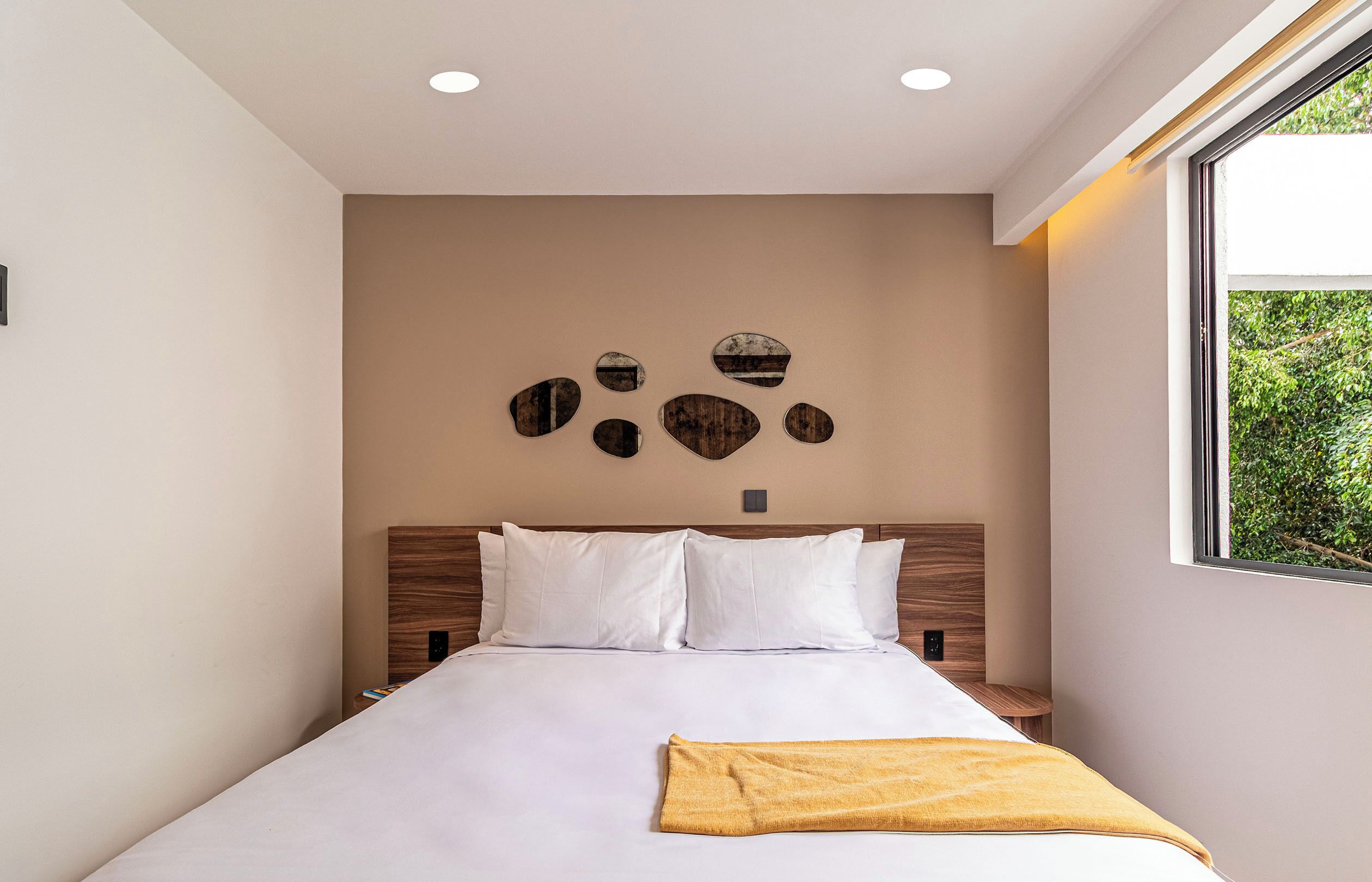 Un dormitorio moderno con una cama grande, un cabecero con panel de madera y un aplique de pared.