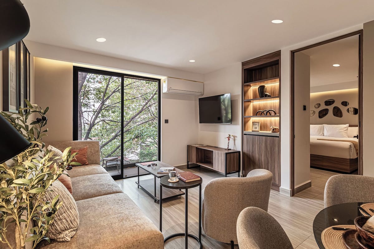Una sala de estar moderna con sofá, mesa de centro, sillas, televisor y estantería.
