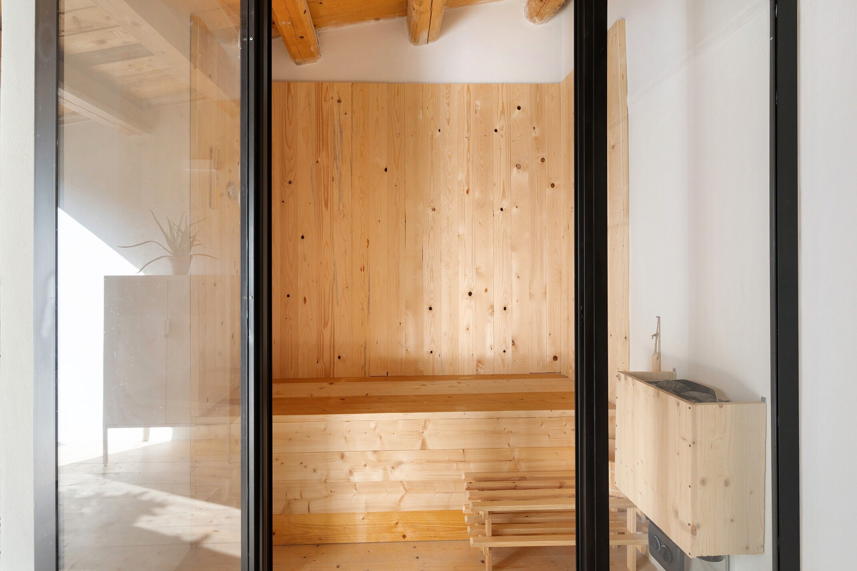 A room with wooden panel walls, a glass door, and a small wooden structure at the far end.
