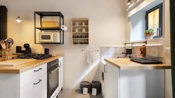 Een kleine keuken met een magnetron, fornuis en planken voor opslag.