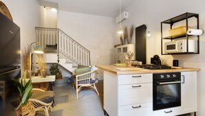Une cuisine compacte dotée d’un four encastré, d’une cuisinière à gaz et de meubles de rangement blancs.
