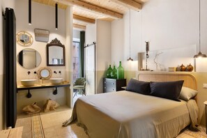 Een slaapkamer met een bed, nachtkastje en uitzicht op buiten.