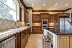 A kitchen with wooden cabinets, a stainless steel sink, an oven, and a refrigerator.