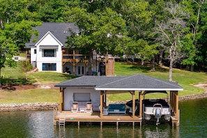 A lakeside house with a dock, outdoor seating, and a boat.